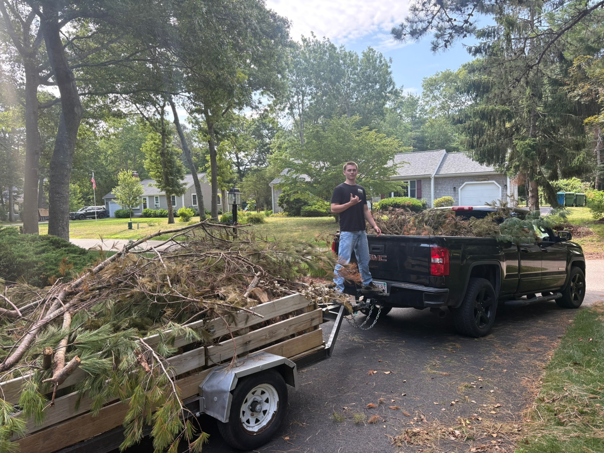 Trailer loaded with brush and yard debris on a Cape Cod driveway